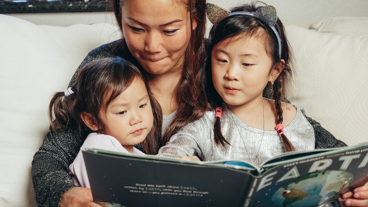 Mother and two children reading a book together, fostering closeness and learning at home.